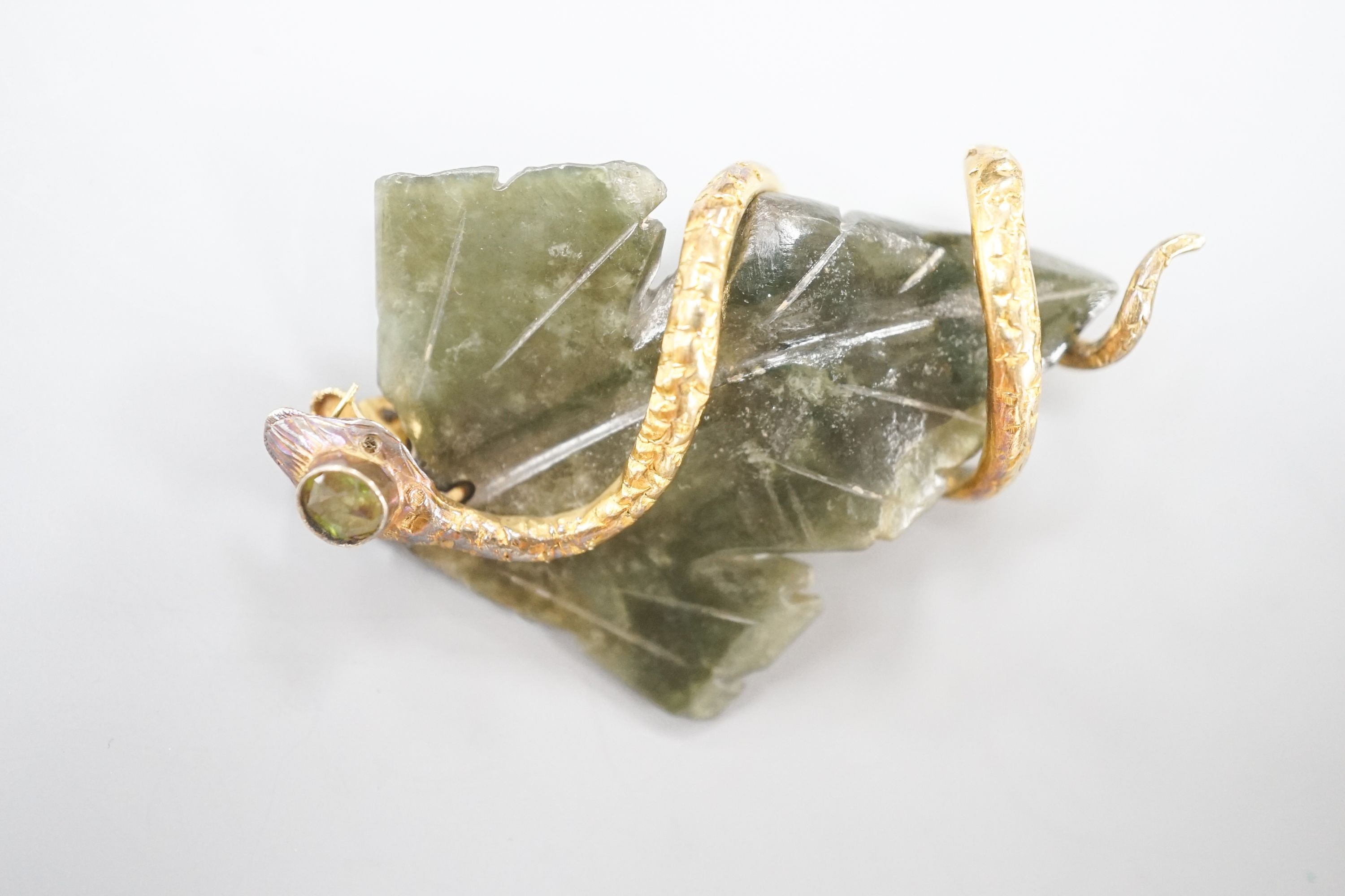 A continental yellow metal, garnet and nephrite set brooch, modelled as a leaf entwined with serpent, 56mm, gross weight 14 grams.